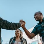 A friendly handshake between a police officer and a civilian during an outdoor community event.